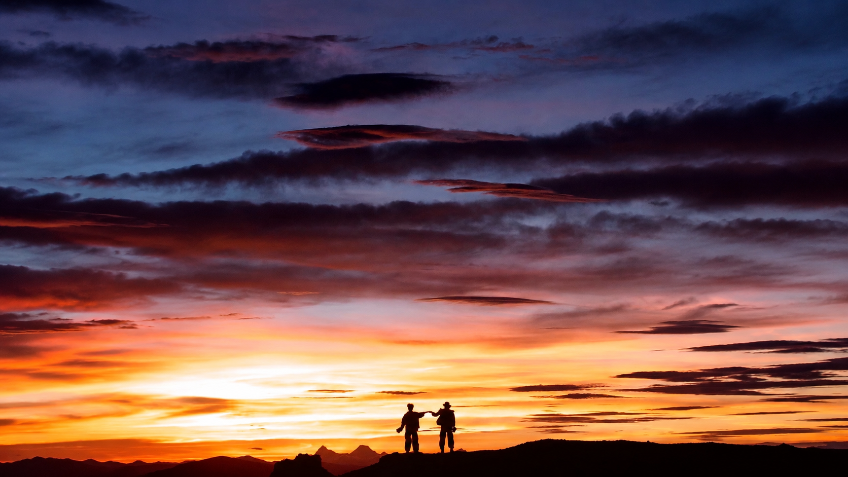 Two collaborators standing together against a vivid sunset after building a website as a team